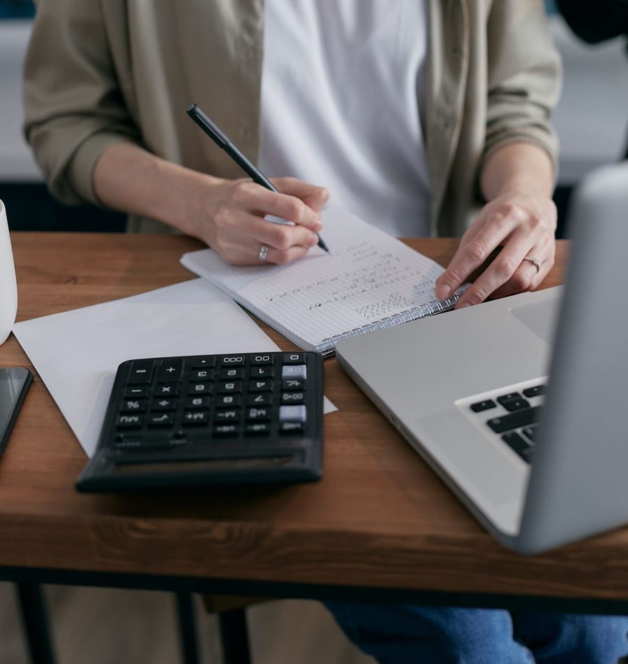 Hands reviewing a budget with a calculator and notebook.