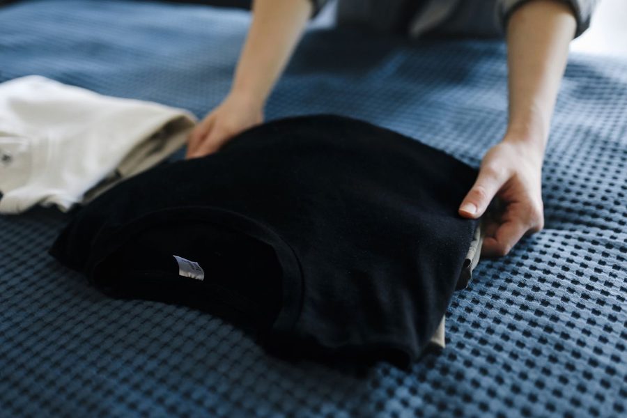 A black garment being folded carefully after washing.