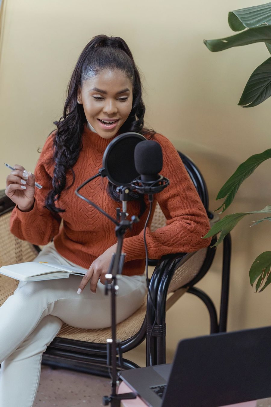 A woman speaking into a microphone while recording a podcast.