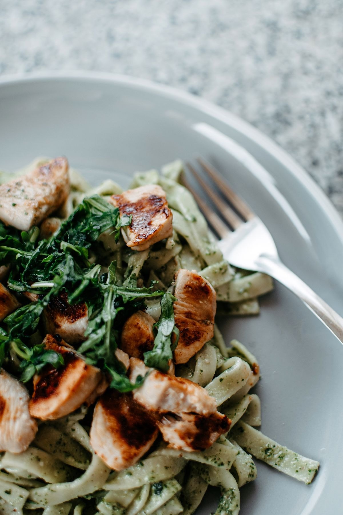 Chicken pesto pasta served on a white plate