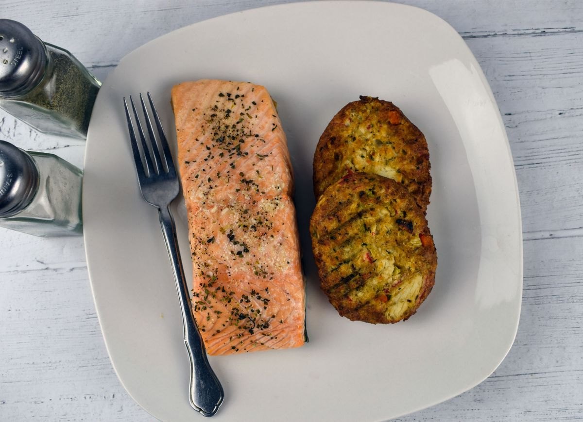 Seasoned salmon with crab cakes on a white plate